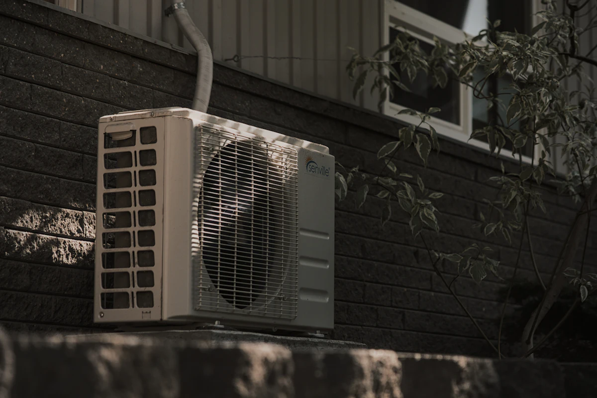 Outdoor air conditioner unit beside a brick wall