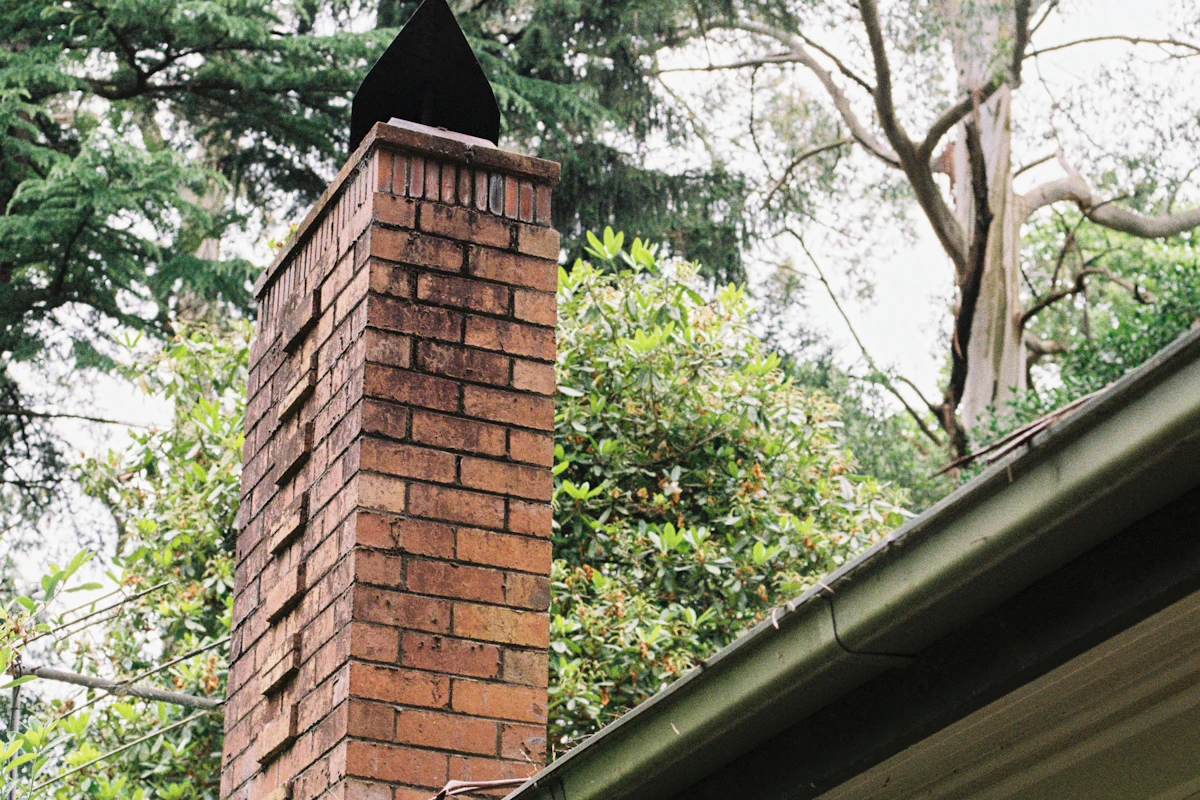 Brick chimney on a home surrounded by trees