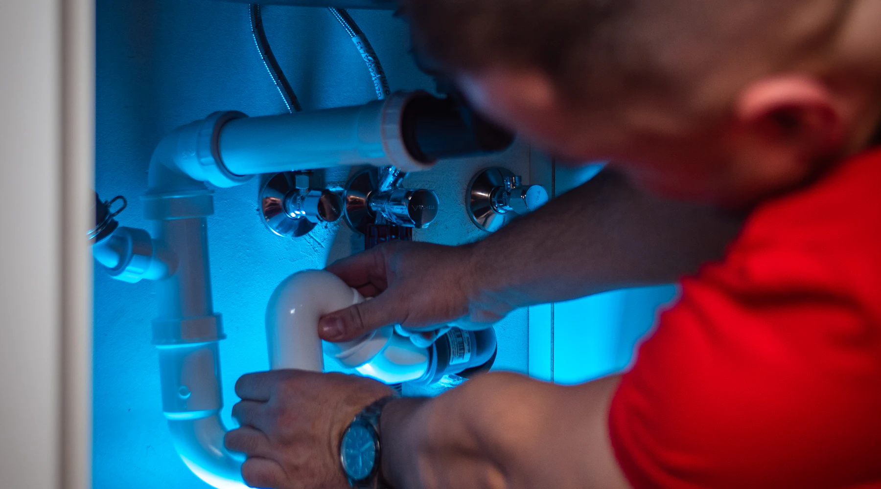 Plumber working on the drain pipes under a sink
