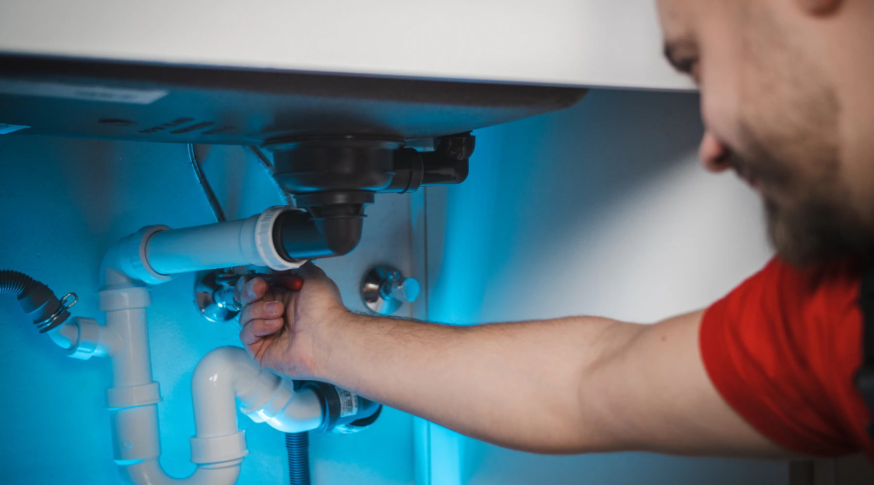 Plumber repairing a pipe inside a wall
