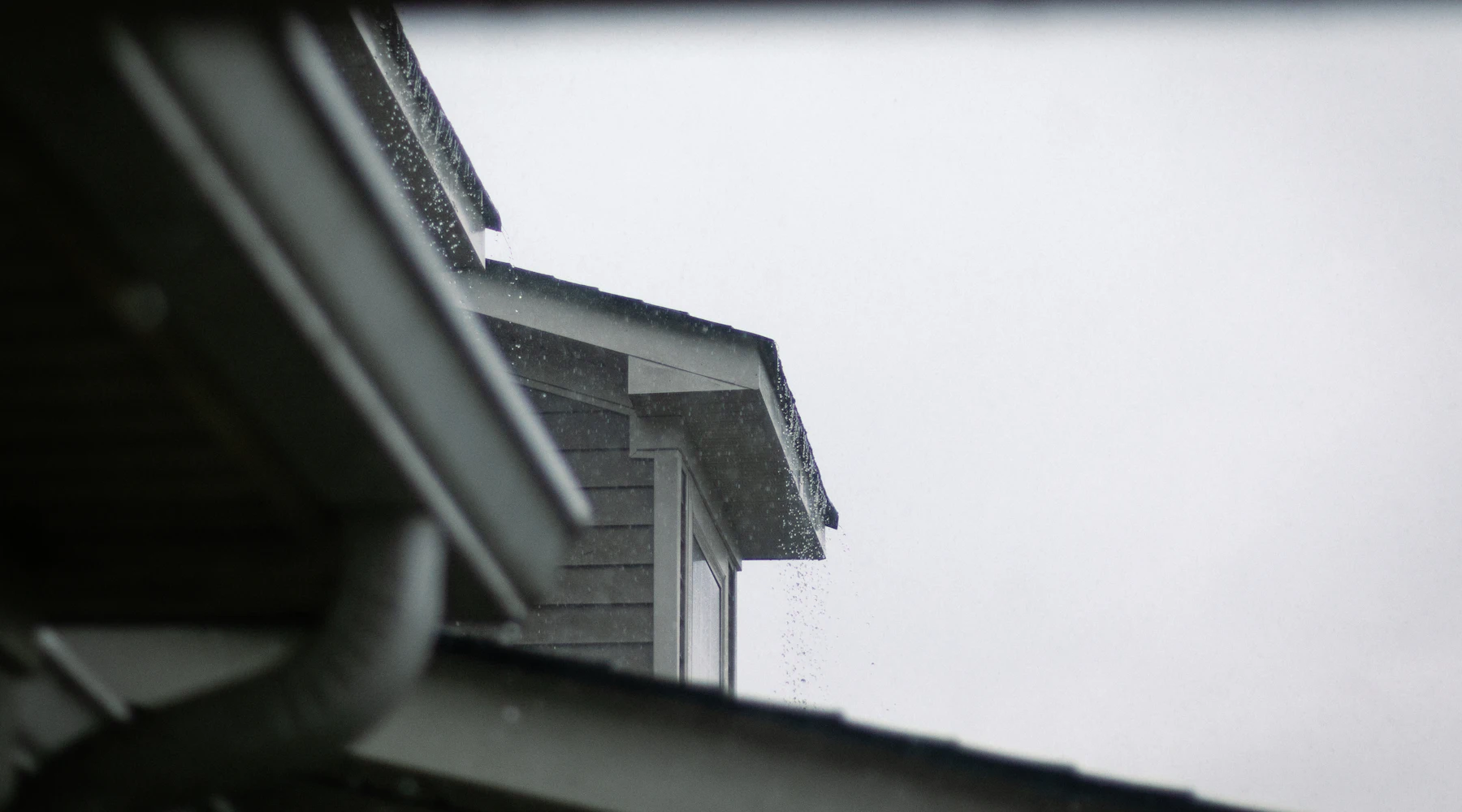 Rain gutters and downspout along a roof edge
