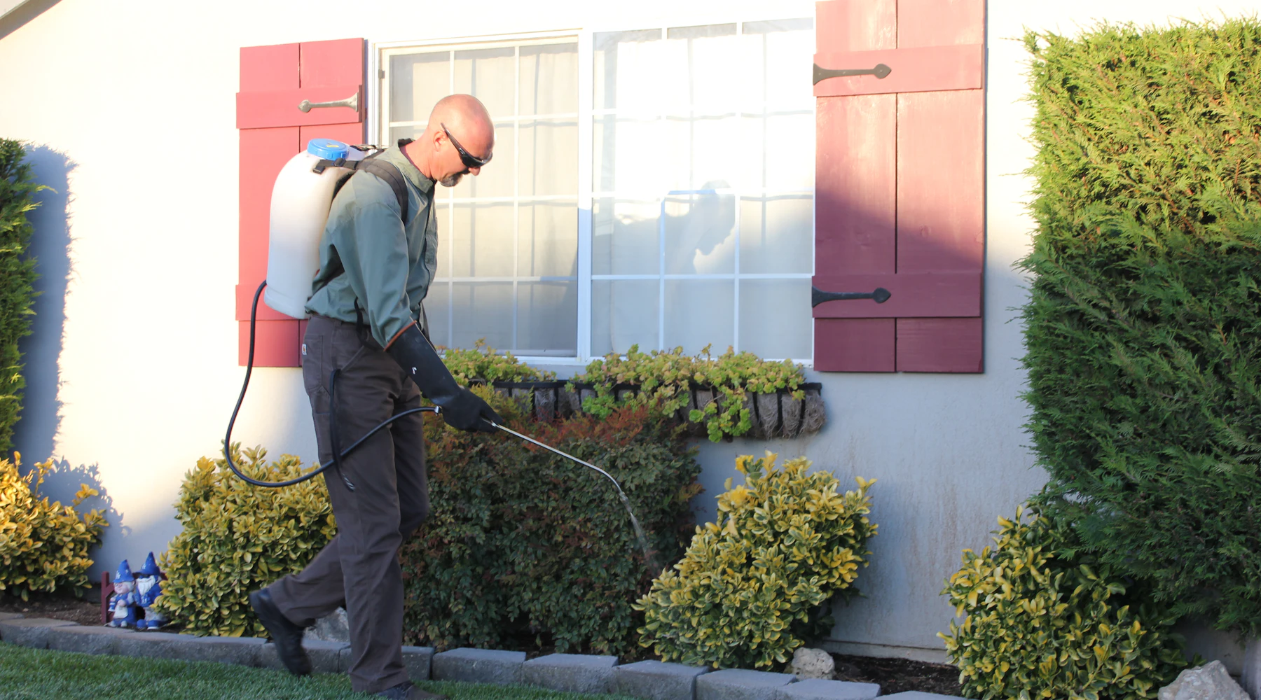 Pest control technician in front of a home
